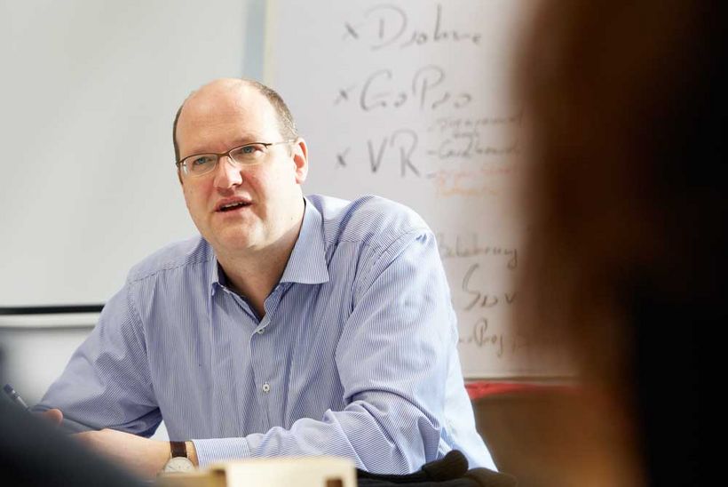 Henning Fietze sitzt an einem Tisch und unterhält sich