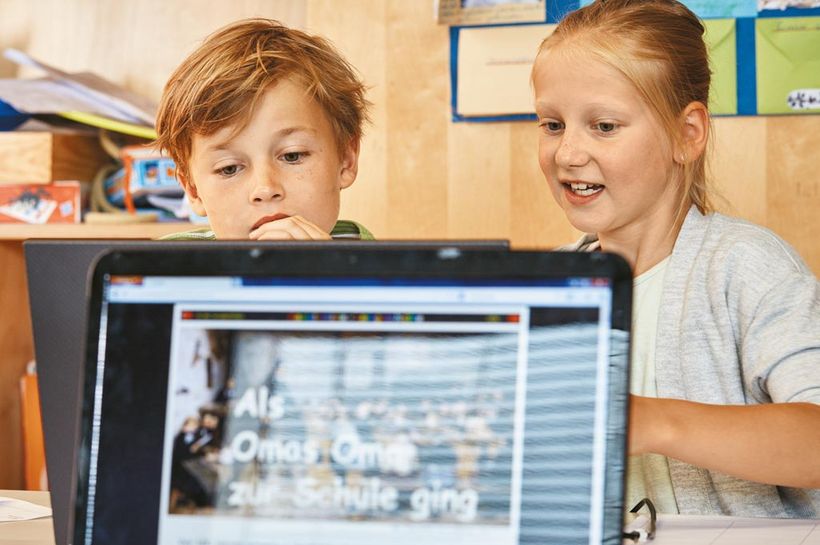 Ein Mädchen und ein Junge sitzen zusammen am Laptop