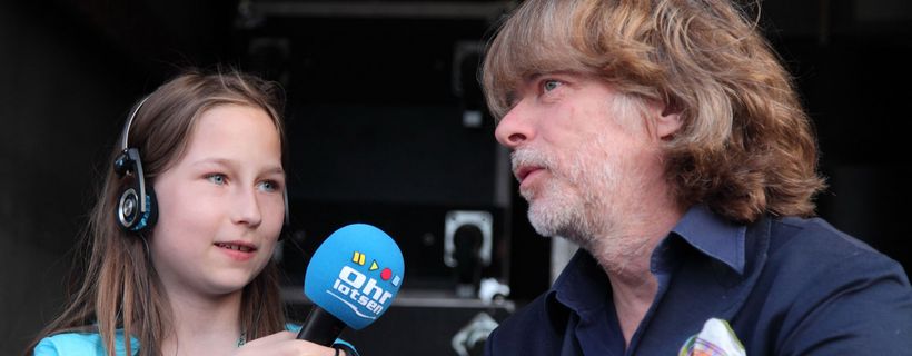 Ein Mädchen hält Helge Schneider ein Mikrofon hin
