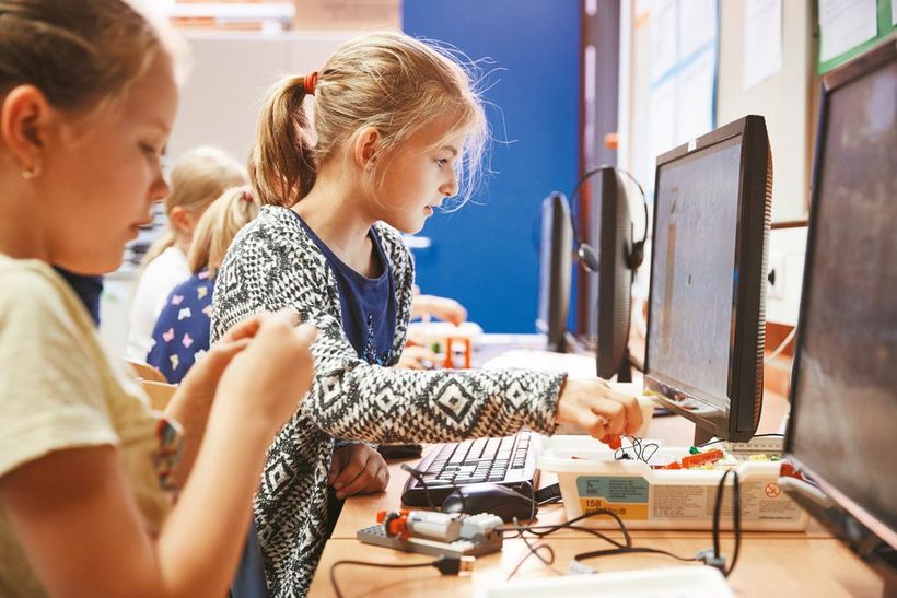 Zwei Mädels sitzen an Computern und programmieren