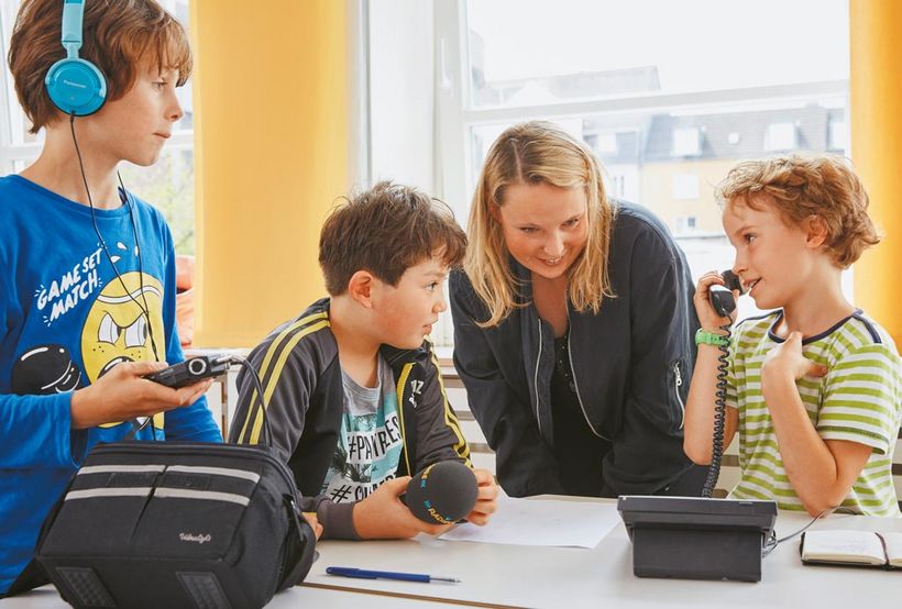 Journalistin Sarah Reinhardt von den Radiofüchsen bei der Arbeit mit drei Jungs