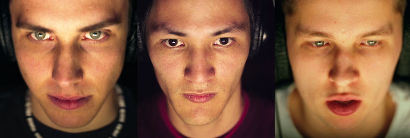 Gesichter von drei jungen Männern, die Kopfhörer tragen und auf einen Bildschirm schauen