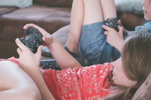 Zwei Kinder fläzen auf dem Bett und spielen Videospiele