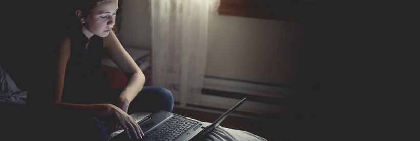 Ein junges Mädchen sitzt auf Ihrem Bett am Laptop