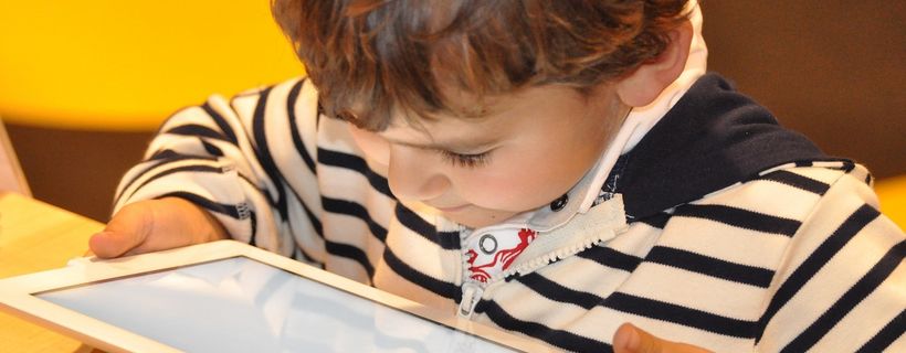 Ein kleiner Junge schaut auf ein Tablet, das er in seinen Händen hält