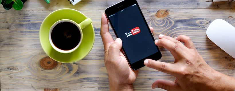 Zwei Hände halten ein Smartphone mit YouTube-App