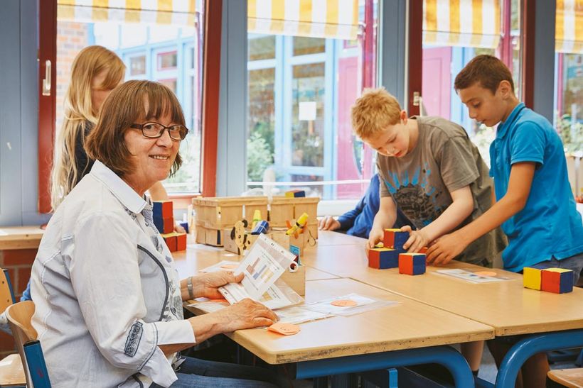 Gisela Blankenburg sitzt zusammen mit ein paar Schülern am Tisch