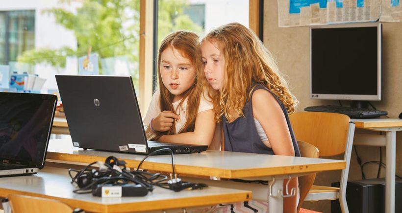 Zwei Zweitklässlerinnen sitzen zusammen an einem Laptop